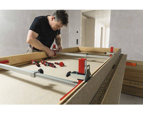 Muž pracuje s rozpierakom zárubní dverí na ráme dverí