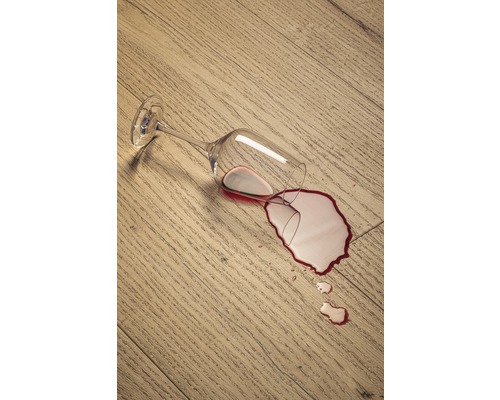 Prevrhnutý pohár na víno na drevenej podlahe s rozliatym vínom