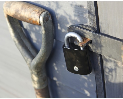 Rýľ a visiaci zámok na drevených dverách