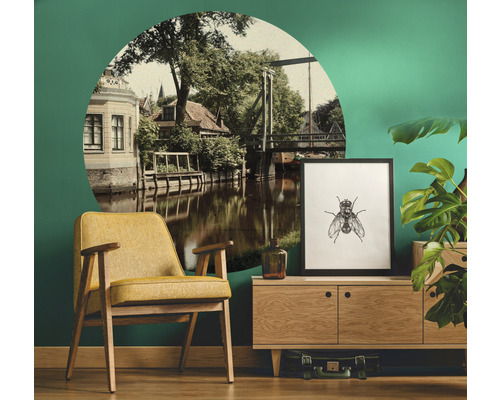 Obývacia izba so žltým kreslom, komodou, rastlinou a nástennou dekoráciou s motívom rieky