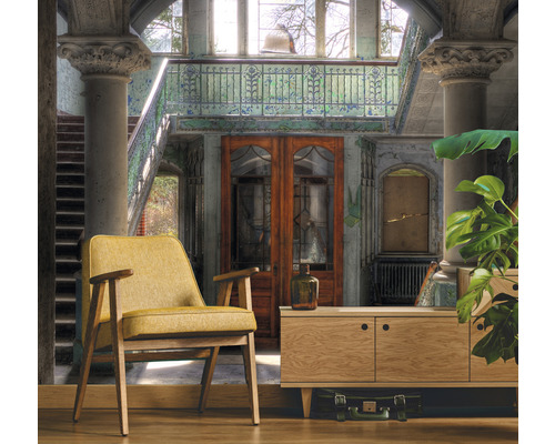 Interiérová fotografia miestnosti s kreslom, skrinkou a dekoráciami v budove so schodiskom