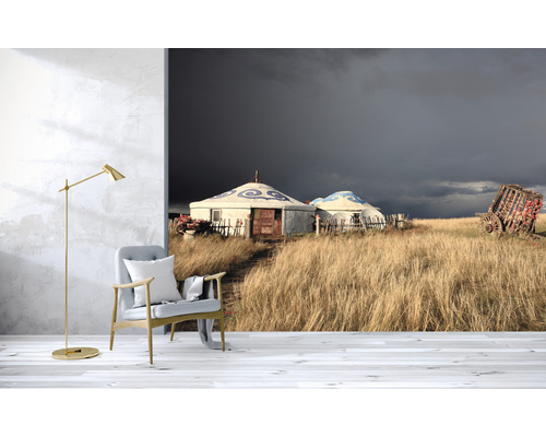Obývacia izba s fototapetou zobrazujúcou jurty v trávnatej krajine pod tmavou oblohou.