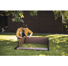 Muž zostavuje vyvýšený záhon v záhrade.