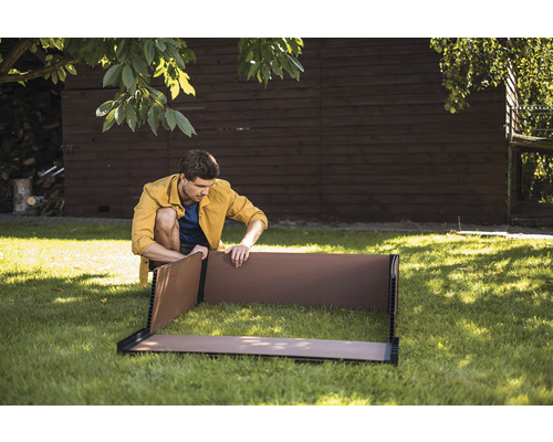 Muž zostavuje vyvýšený záhon v záhrade.