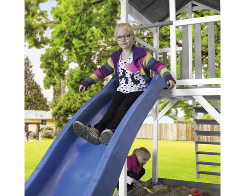 Dievča sa kĺže na modrej šmýkačke hracej veže v záhrade