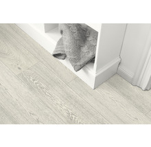 Svetlá drevená podlaha vedľa bielej police s pletenou dekou