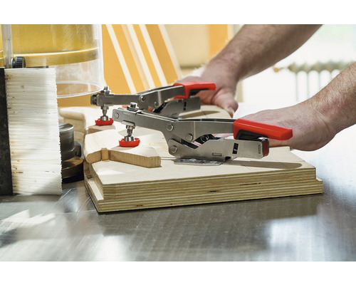 Dva pákové svorky upevňujú kus dreva.