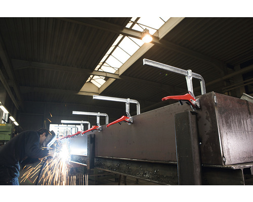 Zvárač pracuje na kuse kovu, ktorý je upevnený rýchloupínacími svorkami.