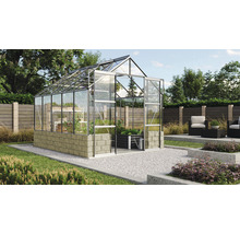 Skleník so sklenenými panelmi a kamennou základňou v záhrade