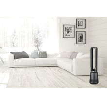 Obývacia izba s vežovým ventilátorom, pohovkou a dekoráciami.
