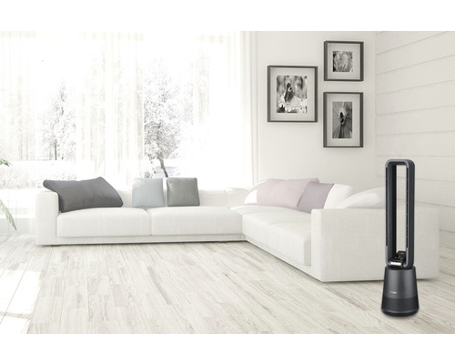 Obývacia izba s vežovým ventilátorom, pohovkou a dekoráciami.