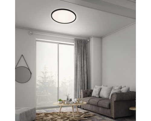 Obývacia izba so stropným svietidlom okrúhleho tvaru, pohovkou a závesmi.