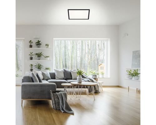 Obývacia izba so sivou rohovou sedacou súpravou, drevenou podlahou a štvorcovým stropným svietidlom