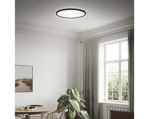 Svetlá miestnosť s okrúhlym stropným svietidlom, stolom a oknom.