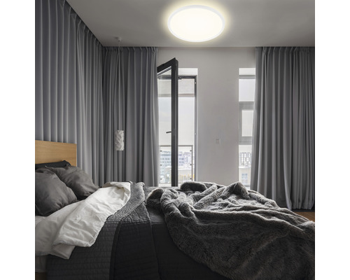 Spálňa s posteľou, závesmi a okrúhlym stropným svietidlom