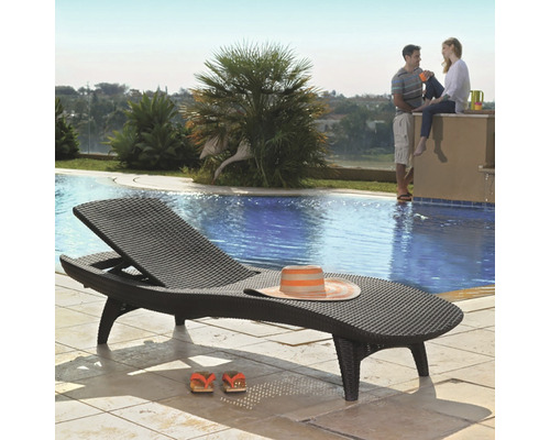 Prútené ležadlo s klobúkom a sandálmi pri bazéne