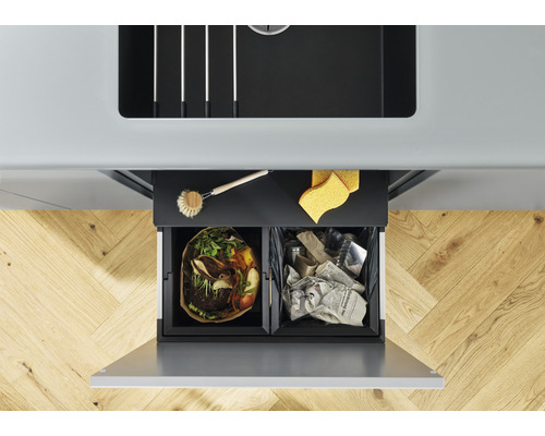 Pohľad zhora na kôš na triedený odpad s dvoma priehradkami pod drezom, naplnený organickým odpadom a starým papierom.