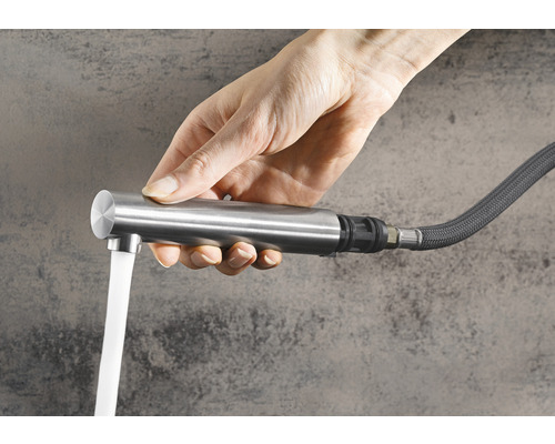 Ruka drží vodovodný kohútik s tečúcou vodou