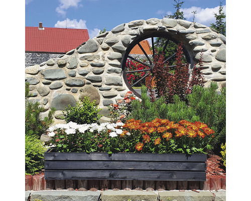 Kvetináč s kvetmi pred stenou s dekoráciou kolesa