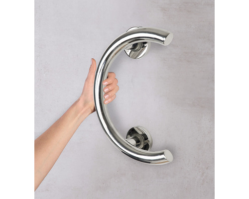 Osoba drží ohnuté madlo z nehrdzavejúcej ocele na stene.