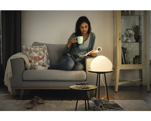 Žena číta časopis na pohovke s lampou na odkladacom stolíku