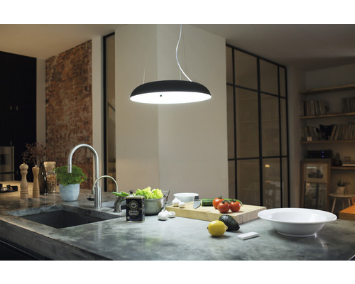 Moderná kuchyňa s drezom, batériou, závesným svietidlom a ingredienciami na pracovnej doske