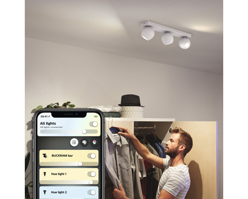 Scéna muža ovládajúceho stropné svietidlo Philips Hue Buckram pomocou aplikácie pre smartfón