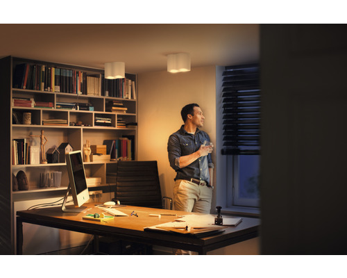 Pracovňa so stolom, policou a mužom, ktorý sa pozerá z okna