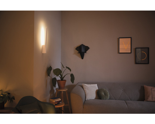 Obývacia izba so sivou pohovkou, nástenným svietidlom, izbovou rastlinou a dekoráciou