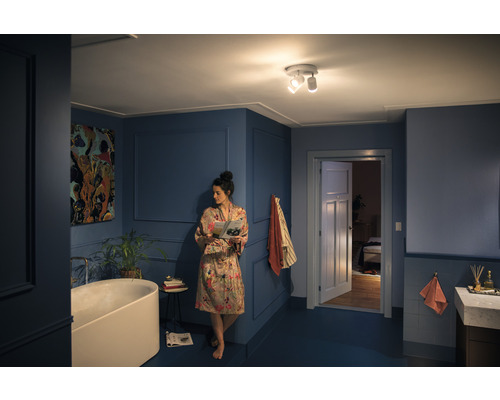 Kúpeľňa s vaňou, stropným svietidlom a ženou čítajúcou časopis