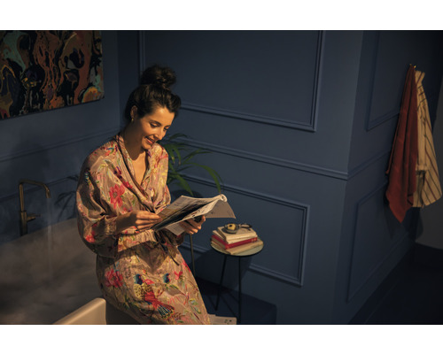 Žena číta noviny v kúpeľni s vaňou a príručným stolíkom