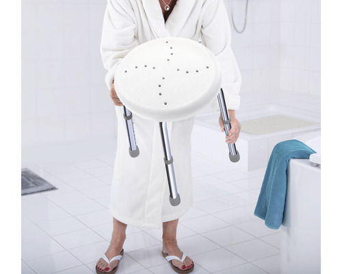 Žena v župane drží sprchovú stoličku s výškovo nastaviteľnými nohami
