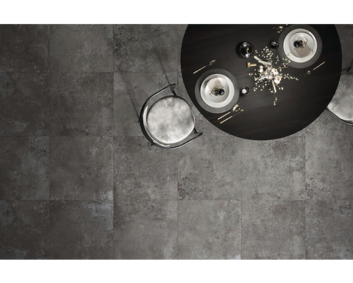 Pohľad zhora na sivú dlažbu s jedálenským stolom a stoličkou