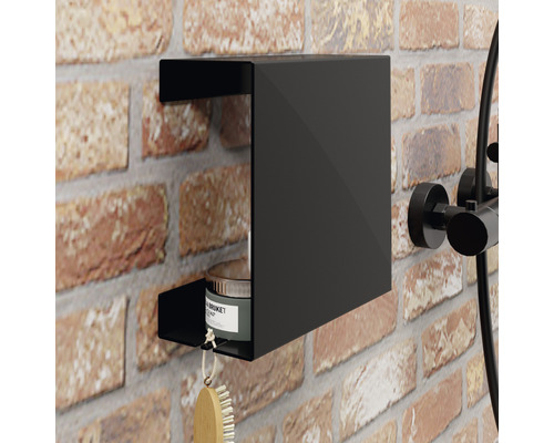 Čierna sprchová polička na tehlovej stene so štetkou a plechovkou