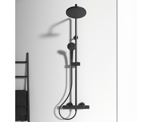Čierna sprchová armatúra s hlavovou a ručnou sprchou namontovaná na stene.