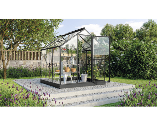 Skleník s policami a otvorenými dverami v záhrade.