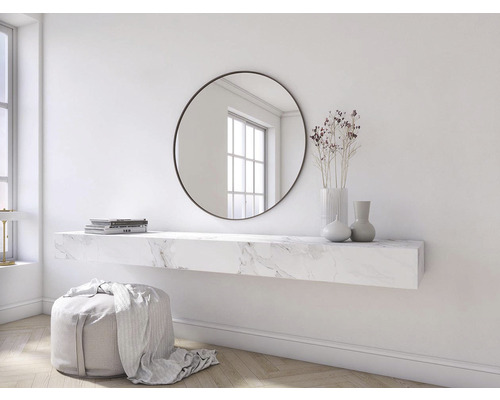 Scéna s okrúhlym zrkadlom, nástennou policou s mramorovým vzhľadom, vázami, knihami a stoličkou.