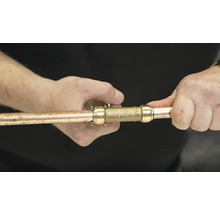 Osoba pripája medenú rúrku ku konektoru.