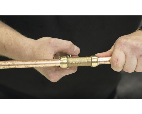 Osoba pripája medenú rúrku ku konektoru.