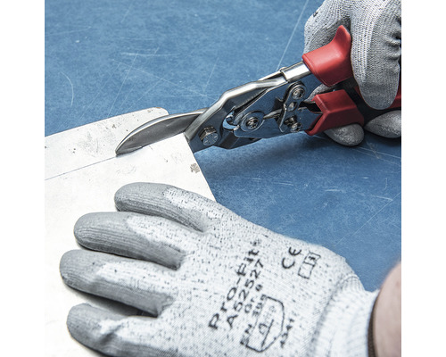 Osoba strihá plech pomocou nožníc na plech.