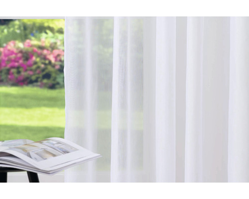 Svetlý, priesvitný záves pred oknom s výhľadom do záhrady