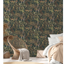 Spálňa s tapetou džungle so zvieracími a rastlinnými motívmi, posteľou a prúteným kreslom