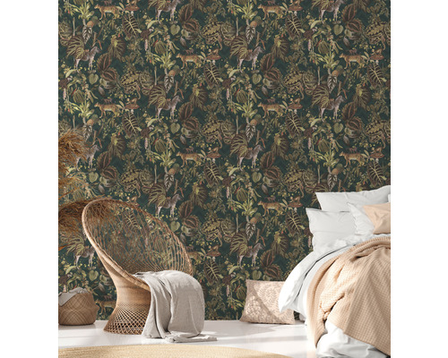 Spálňa s tapetou džungle so zvieracími a rastlinnými motívmi, posteľou a prúteným kreslom