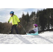 Chlapec ťahá dievča na saniach v snehu