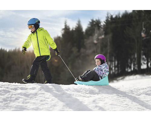 Chlapec ťahá dievča na saniach v snehu