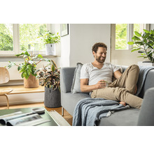 Obývacia izba s mužom na gauči a rastlinami v plstených kvetináčoch