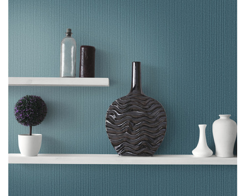 Dekoratívne police s vázami, rastlinou a fľašou pred stenou