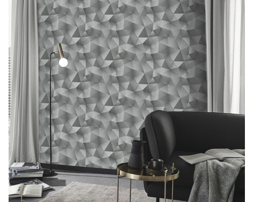 Obývacia izba s geometrickou tapetou, stojacou lampou a pohovkou.