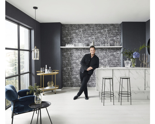 Svetlá miestnosť s barom, stoličkami, kreslom, odkladacím stolíkom a mužom