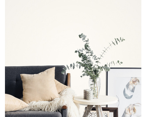 Obývacia izba so sivou pohovkou, vankúšmi, príručným stolíkom, vázou s eukalyptom a rámami na obrazy.